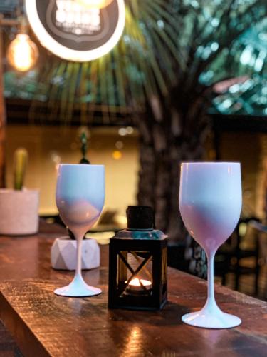 two wine glasses sitting on a table with a candle at RocaMar Hostel Boutique in Punta del Este