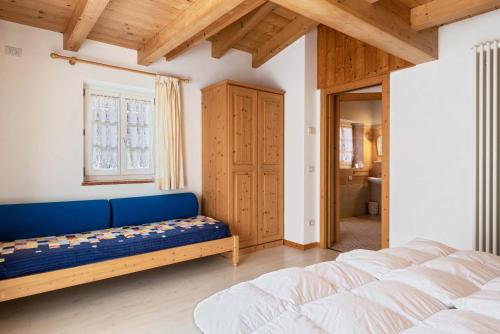 1 dormitorio con 2 camas y sofá azul en Cesa de Agnese en Canazei