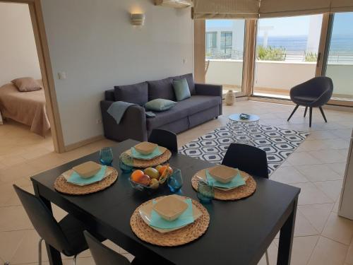 ein Wohnzimmer mit einem Tisch, Stühlen und einem Sofa in der Unterkunft Sesimbra California Beach Apartment in Sesimbra