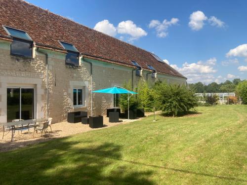 a building with a picnic table and an umbrella at Les Pierres D'aurèle Chambres d'Hôtes in Saint-Georges-sur-Cher
