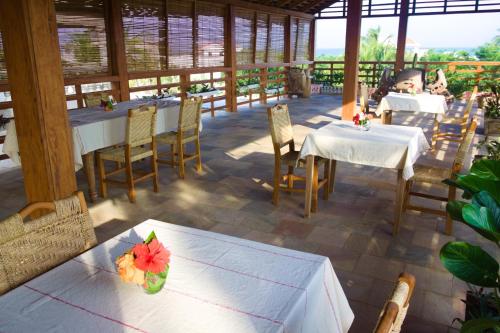um restaurante com mesas e cadeiras e uma mulher sentada à mesa em Hotel Otsunami em Lomé