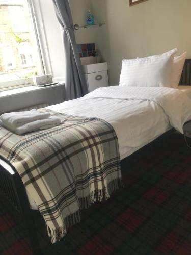 a bed in a room with a white bedspread at Ivy Braveheart Guest House in Edinburgh