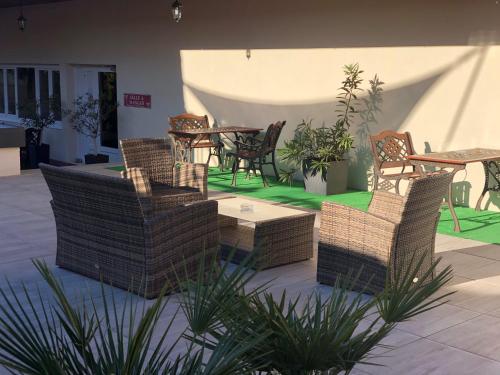 a patio with wicker chairs and a table and tables at The Originals Boutique, Hôtel Clos Sainte Marie, Nevers in Nevers