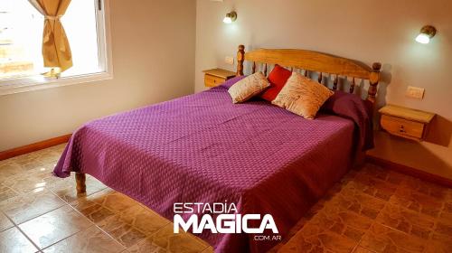 1 dormitorio con cama con colcha púrpura y ventana en Cabañas en Cuadro Nacional en San Rafael