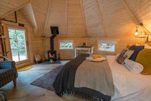 um quarto com uma cama num quarto com uma lareira em Punch Tree Cabins Couples Outdoor Bath em Carluke