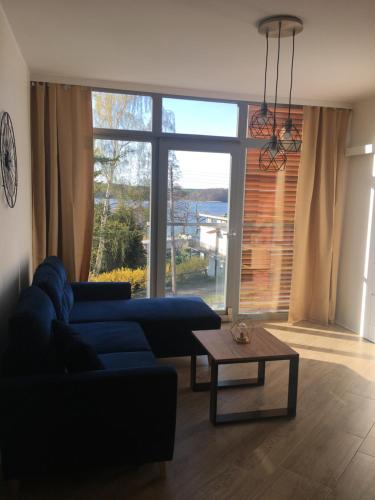 a living room with a blue couch and a table at Nowoczesny Apartament z widokiem na jezioro in Charzykowy