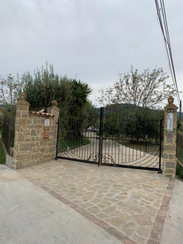 a black gate with a stone pillar and a stone wall at Casa Vacanze Magistro in Patti