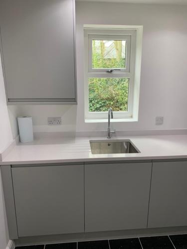 uma cozinha branca com um lavatório e uma janela em Headingley Excellent 1 bedroom apartment em Leeds