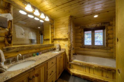 Black Diamond Lodge في Lead: حمام به مغسلتين وحوض استحمام ومرآة