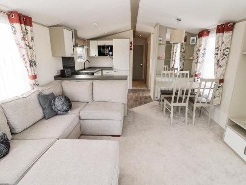 a living room with a couch and a kitchen at Moonlight Lodge in Morpeth