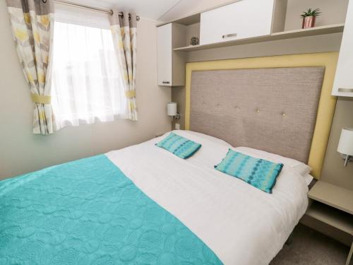 a bedroom with a large bed with two blue pillows at Moonlight Lodge in Morpeth