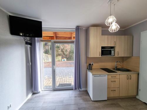 a kitchen with a sink and a refrigerator and a window at Domek pod świerkami in Kudowa-Zdrój