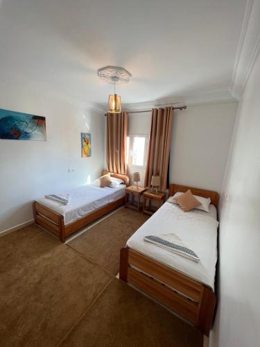 a bedroom with two beds and a window at Dar Surf in Taghazout