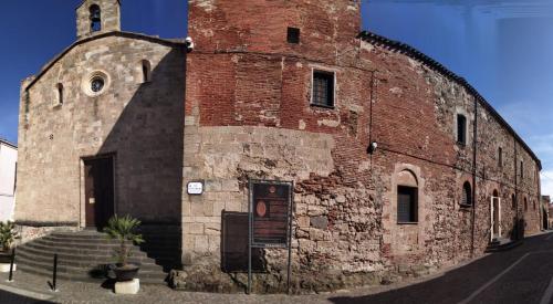 een oud bakstenen gebouw met een klokkentoren bij Monastero Santa Chiara Guest House in Oristano
