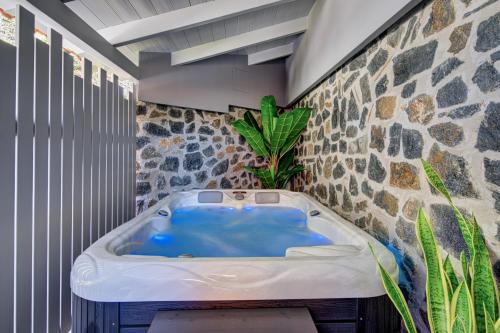 baño con bañera azul y pared de piedra en Kanathos Pigi, en Nauplia
