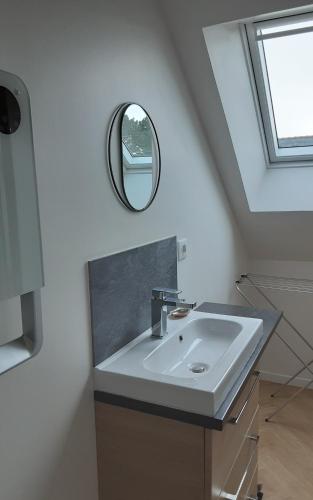 een badkamer met een wastafel en een spiegel aan de muur bij Kerlobek Etoile in Groix