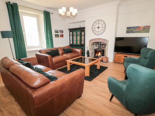 a living room with leather furniture and a fireplace at The Old Sweet Shop in Alnwick