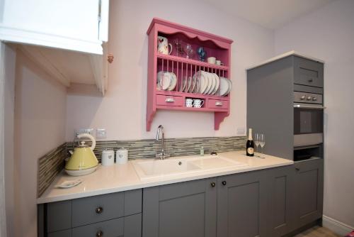 uma cozinha com um lavatório e um armário rosa em The Vault at Westacres em Hexham