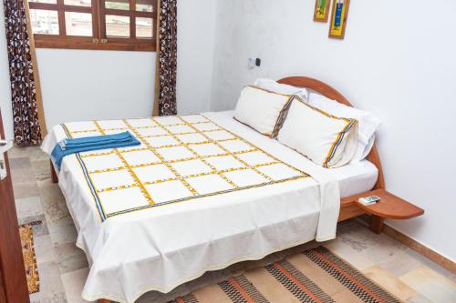 um quarto com uma cama grande e lençóis brancos em Hotel Otsunami em Lomé