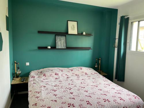 een slaapkamer met een bed en een blauwe muur bij Maison chaleureuse au calme in Roumare
