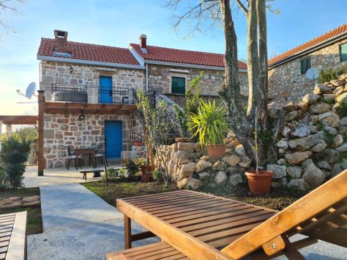 a wooden bench in front of a stone house at Stone house Goranova kuća in Seline