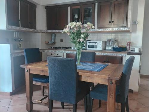 a kitchen with a wooden table with chairs and a vase of flowers at Civico Ventitre in Mentana