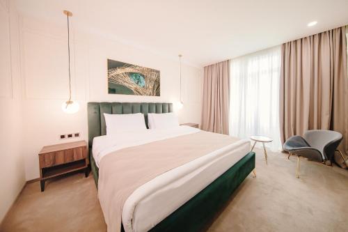 um quarto de hotel com uma cama grande e uma cadeira em Orden Hotel em Tbilisi