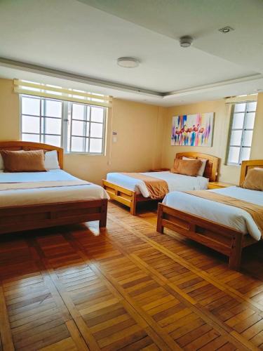 a bedroom with three beds and two windows at Hotel Carolina Montecarlo in Quito
