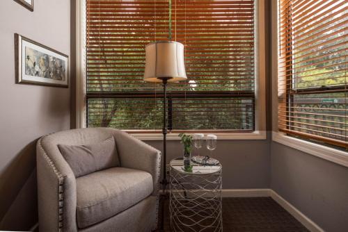 a chair and a lamp in a room with two windows at Inn Above Oak Creek Sedona in Sedona