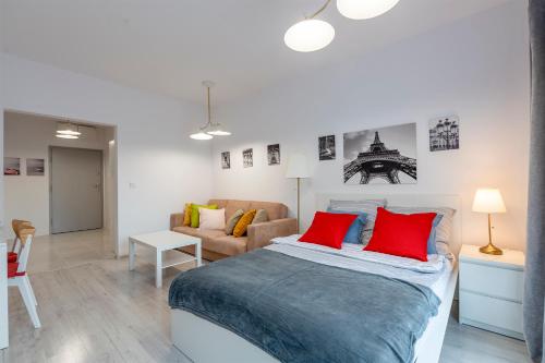 a bedroom with a bed with red pillows and a couch at Luxury in City -3- Studio Bright & Secure Free Parking in Łódź