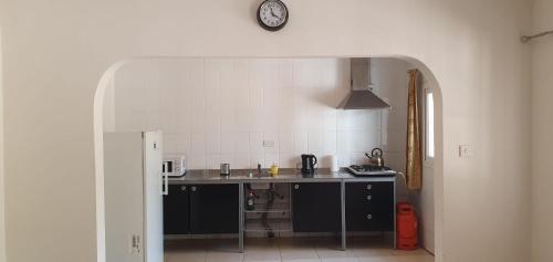 a kitchen with a counter and a clock on the wall at The Rink Apartment's in Sukuta