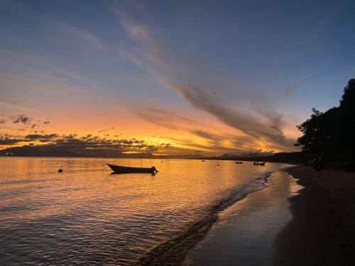 a boat on the shore of a beach at sunset at Marema Pousada in Ilha do Mel