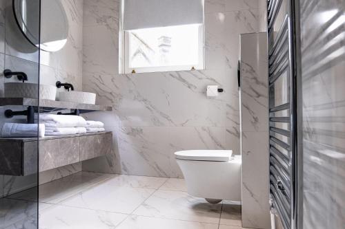 a white bathroom with a toilet and a sink at Andrean House, St Andrews in St Andrews