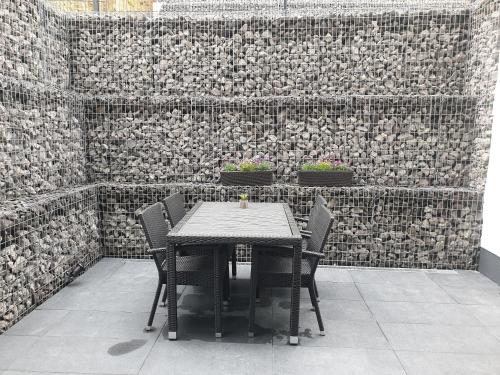 a table and chairs in front of a brick wall at Ferienwohnungen am Aeppelsberg in Volkesfeld