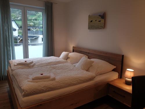 a bedroom with a bed with white sheets and a window at Ferienwohnungen am Aeppelsberg in Volkesfeld