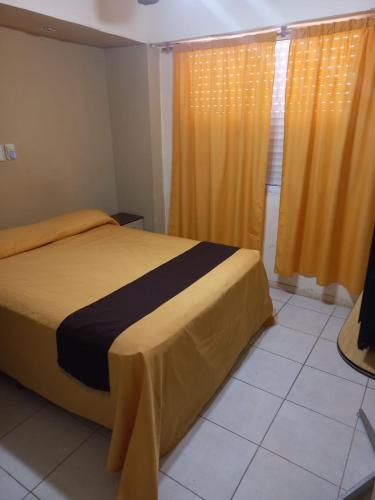a bedroom with a large bed with yellow curtains at San Remo World Hotel in San Clemente del Tuyú