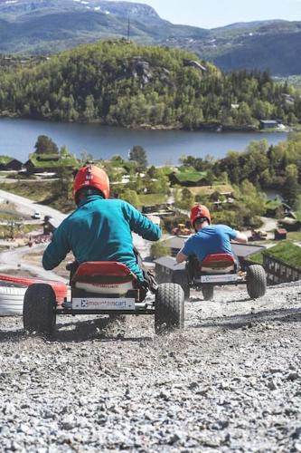 two people riding on toy cars on a gravel road at Holiday cottage with sauna close to Kjeragbolten-Bedding included in Tjørhom