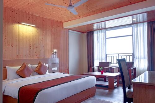 a hotel room with a bed and a desk and a window at Treenz Hotel in Gangtok