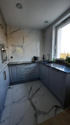 a kitchen with marble counters and a sink and a window at Apartament Widok z tarasami in Ostróda