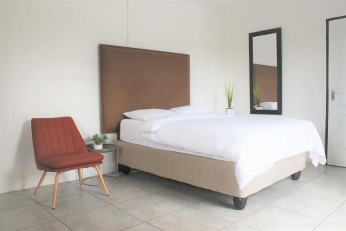 a bedroom with a large bed and a red chair at Cosmo Sleepover in Roodepoort