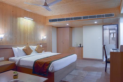 a bedroom with a bed and a desk and a tv at Treenz Hotel in Gangtok