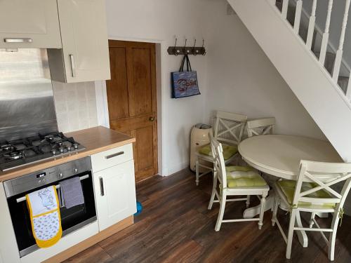 a kitchen with a table and a stove and a sink at April Cottage Ringwood in Ringwood