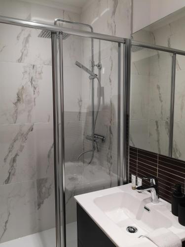 une salle de bain blanche avec une douche et un lavabo dans l'établissement Studio - Le Clos du fond cailloux, à Longuenesse