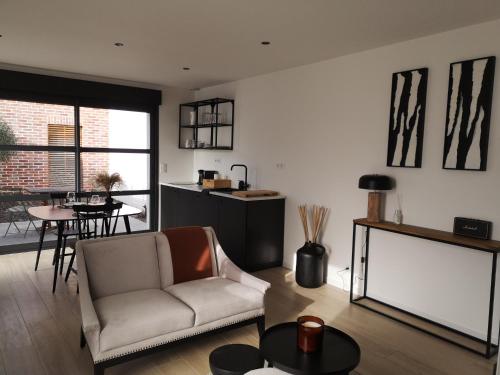 een woonkamer met een bank en een tafel bij Studio - Le Clos du fond cailloux in Longuenesse