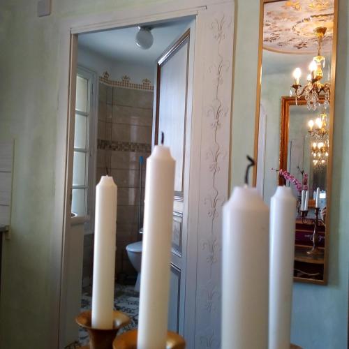 un groupe de bougies blanches devant un miroir dans l'établissement Appartement de Ville Médiévale, à Vinça