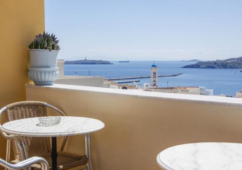 a table and chairs on a balcony with a view of the ocean at Pefkakia Park in Ermoupoli