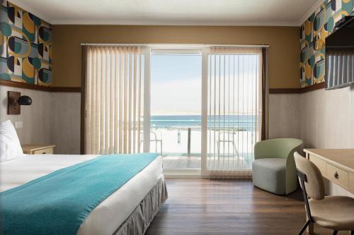 a hotel room with a bed and a view of the ocean at Hotel Rocas de Bahía in Bahia Inglesa