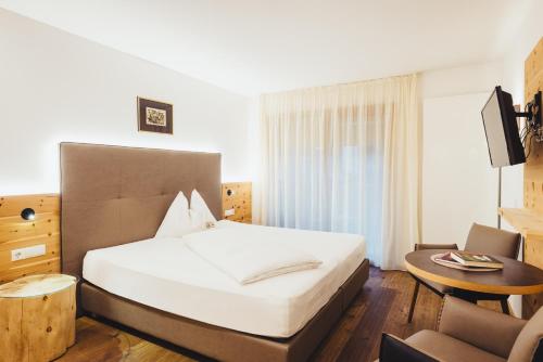 a bedroom with a large white bed and a couch at Hotel Schmuckhof in Chiusa
