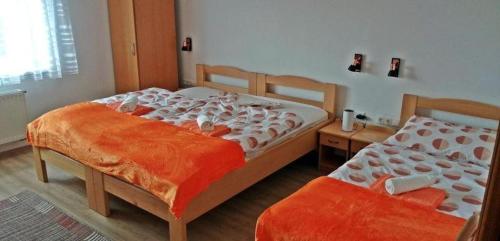 1 dormitorio con 2 camas con sábanas de color naranja en Szentmárton Vendégház, en Tótszentmárton