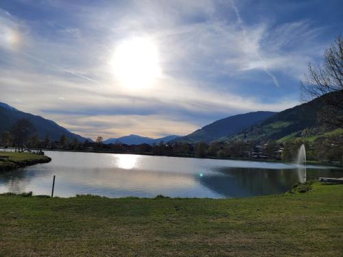 a view of a lake with a fountain and mountains at Profelt`s Apartments Uttendorf - Steinbock Lodges in Uttendorf